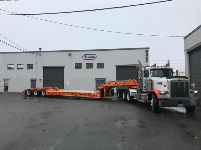 Orange tri-axle 55 ton lowbed with wood deck, hitched for winter delivery at the Pacesetter yard, photo 3 of 14